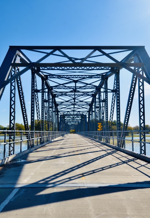 Bridge with a paved pedestrian trail over a lake on a sunny day