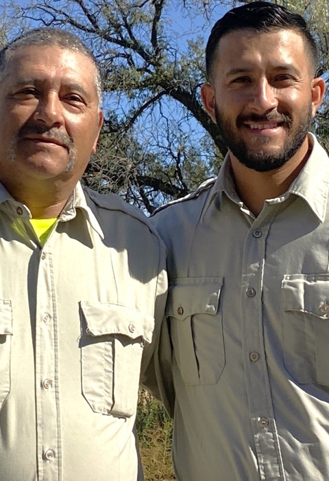 Two men in uniform smiling in an outdoor setting