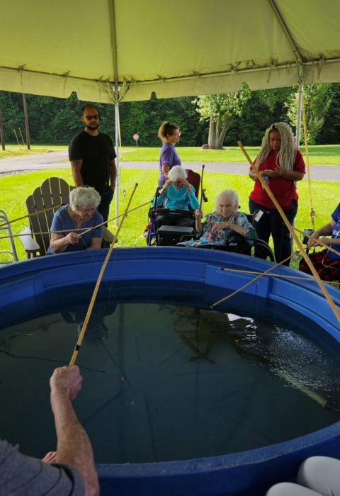 Elderly people fishing out of tub with cane poles