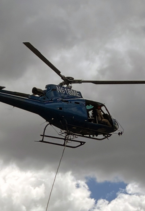 a helicopter hoovers in a cloudy sky