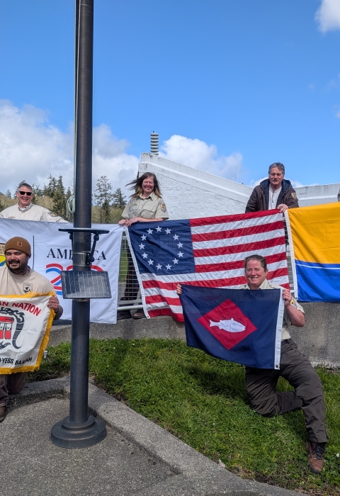6 people on hill holding 4 flags, fish pennant
