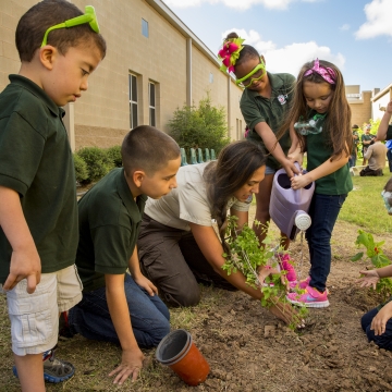 Young children help a refuge leader plant a pollinator garden at their elementary school in Texas.