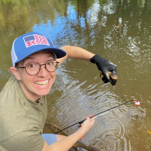 A person holds a small fish.