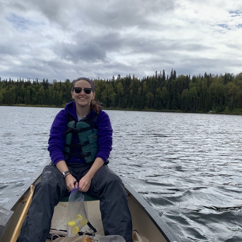 Kaitlyn sits in a canoe sampling fish. 