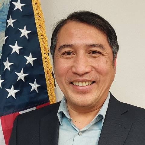 Head of smiling man, next to American flag