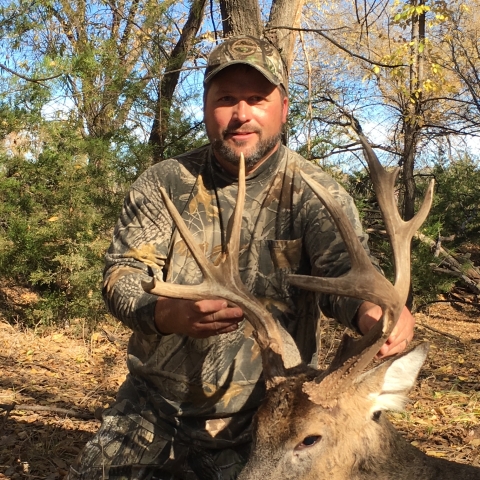 Robbie in camouflage holding the antlers of a deer he hunted. 