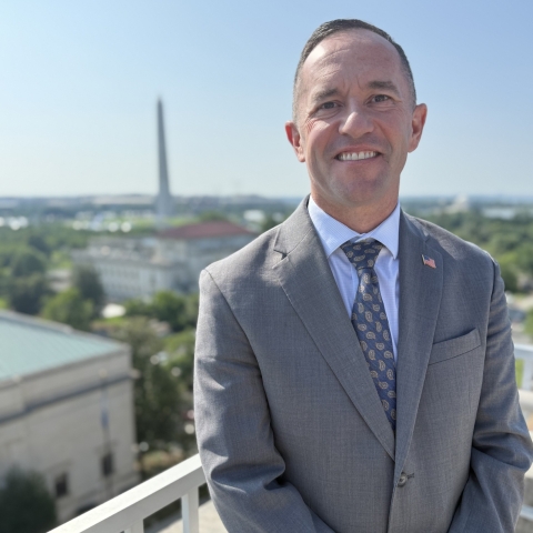 man on balcony with Washington Monument in background