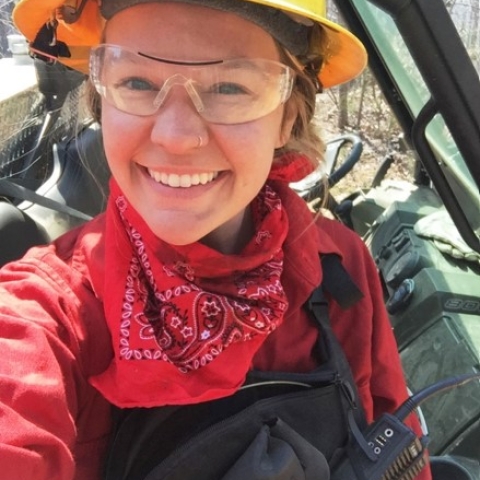 Alex smiling in a yellow construction hat, goggles, and a red bandana