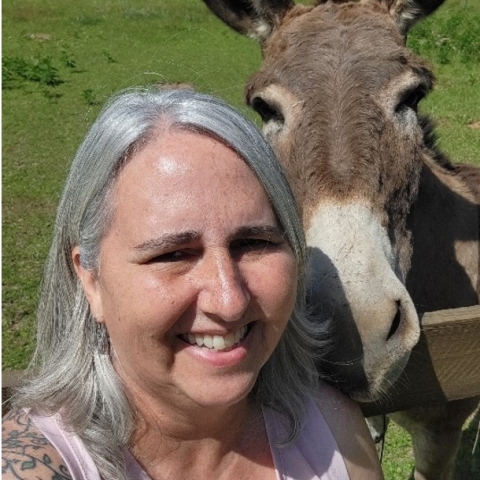 Beth smiles next to a donkey