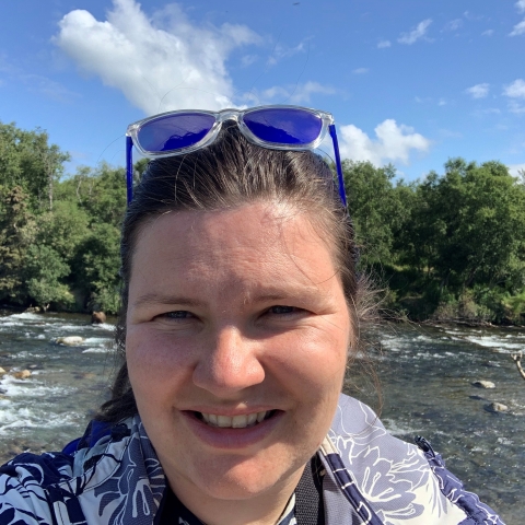 A picture of a woman's face with a river and trees in the background