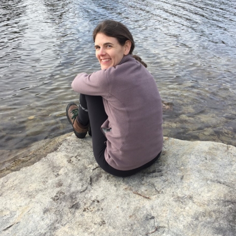 Person sitting on a rock next to water