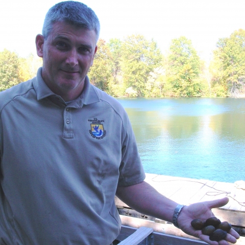 FWS employee holding mussels with river in background