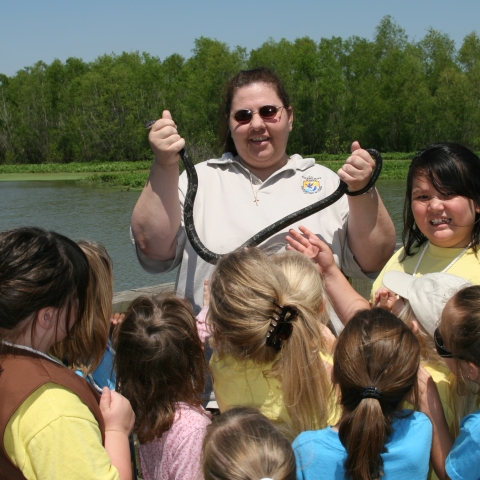Earth Day event with Bonnie Campisi holding a snake with children gathered around