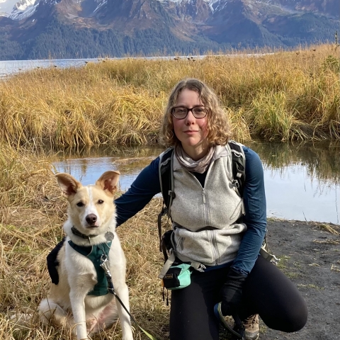 woman next to dog with mountains in the background