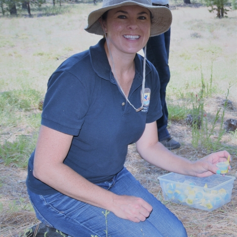 woman in blue Service shirt and tan hat kneeling on ground