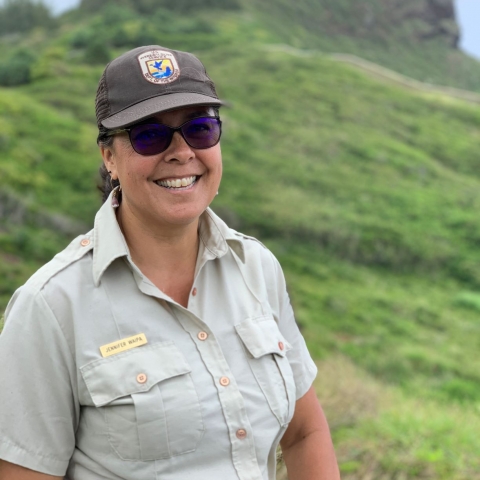woman wearing USFWS uniform stands on a hillside. 