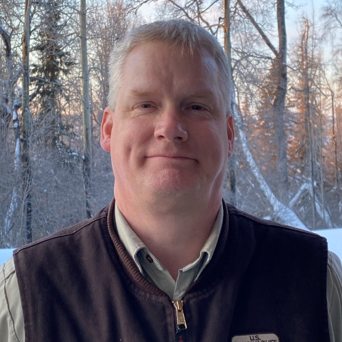 man stands in front of snowy trees
