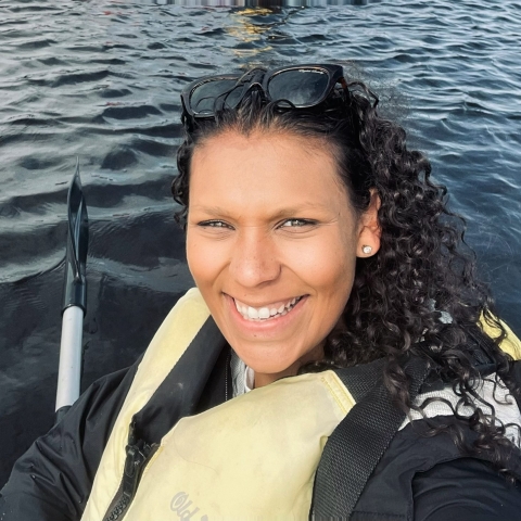 A close-up of a smiling woman paddling on water