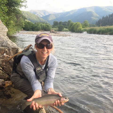 Staff photo of biologist holding a trout at a river in Montana.