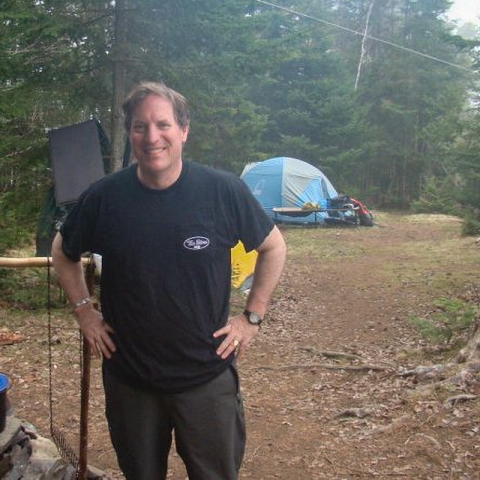 man smiling while standing with hand on hips with tent in background