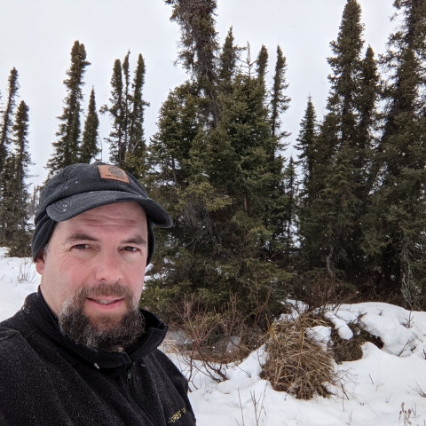 man stands in front of snowy trees