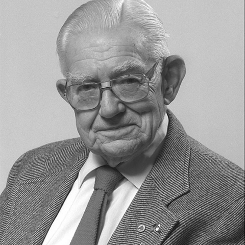 older man wearing glasses with suit and tie posing for photo