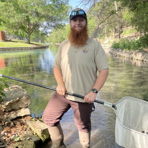 Braden West in Comal River holding a dip net