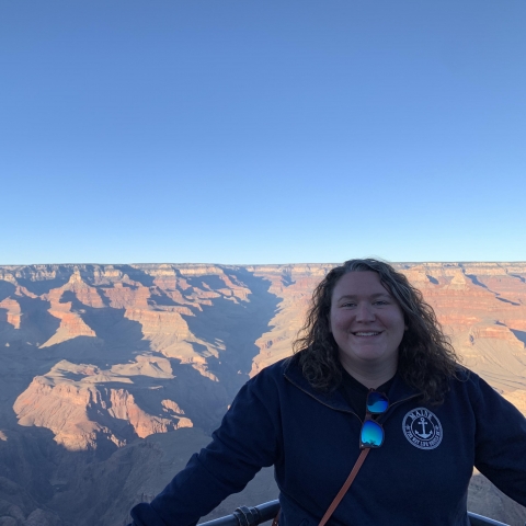 Rachel Stearns, biological technician at Rachel Carson National Wildlife Refuge, poses before a southwestern panorama of canyonlands with bright blue ski above.