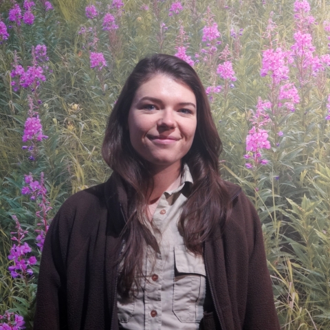 woman in usfws uniform in front of fireweed