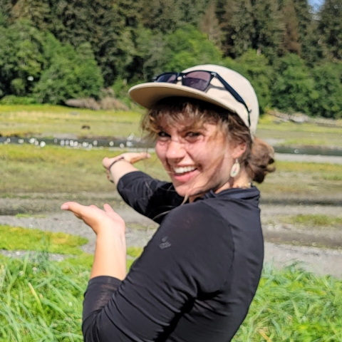 Woman in riparian area gesturing toward birds in the background.