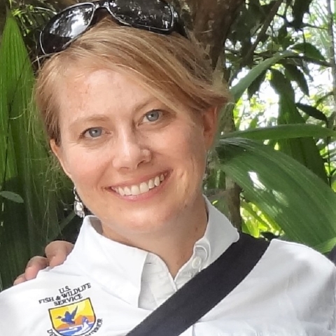 Close-up of a blonde woman smiling and wearing a white collared shirt with the U.S. Fish and Wildlife Service.