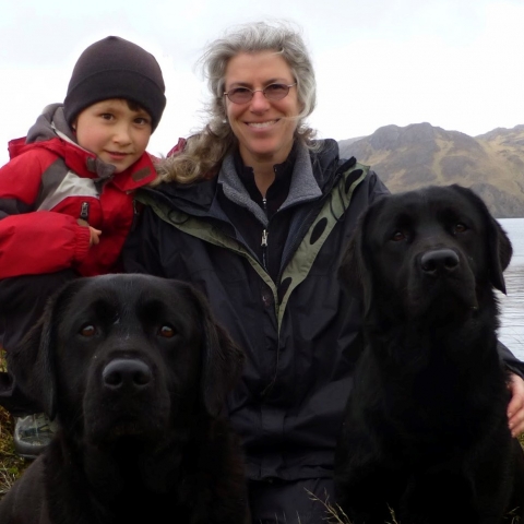 Woman and child with two black labs in the foreground.