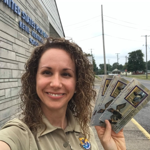 An image of a staff member holding Duck Stamps.