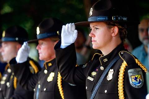 Three US Fish and Wildlife Officers salute in dress uniforms