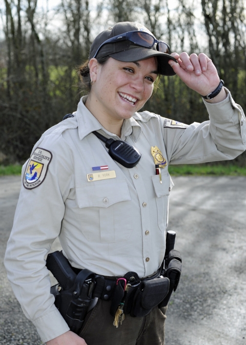 A Federal Wildlife Officer smiles at the camera, tilting her hat