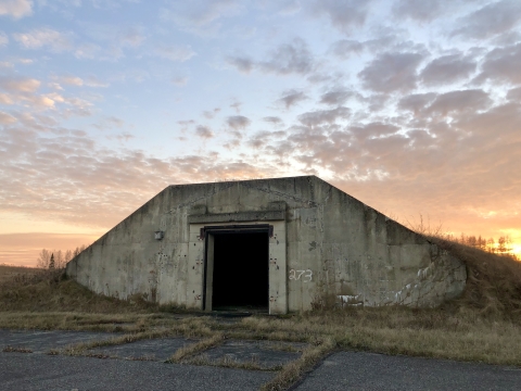 Sun setting over a Cold War era bunker at Aroostook National Wildlife Refuge, evidence of its past military history as a former Air Force base. 