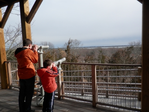 Two youths at the viewing scope located on the observation tower at Kettle Pond Visitor Center's Ocean View Trail.