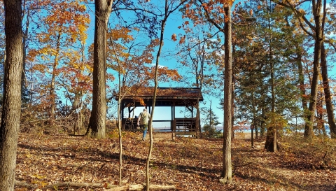A hiker walks up to a wooden structure overlooking a marsh.
