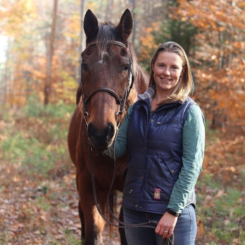 Bri Benvenuti, biological technician at Rachel Carson National Wildlife Refuge, poses with her horse Marshall. The two are framed by soft fall colors in the background