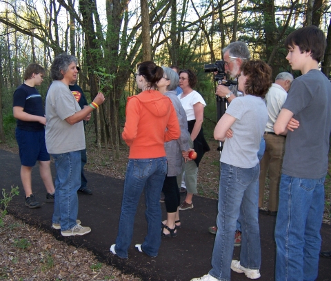 Naturalist shows tree leaf to group on hike