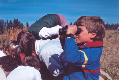 A young boy with binoculars bird watching at Turnbull National Wildlife Refuge