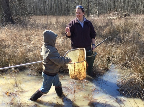 Young boy and FWS biologist catching frogs in net at Big Oaks NWR