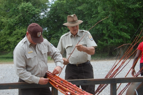 Two USFWS Staff members preparing fishing poles for children to fish with