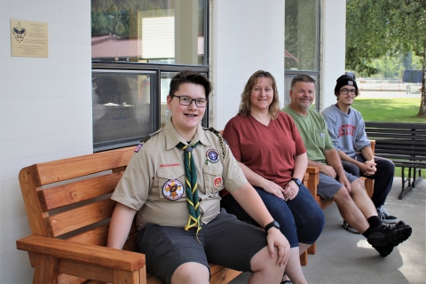 Boy scout Connor Hawk and his family pose on the wooden benches he made in front of Leavenworth NFH.