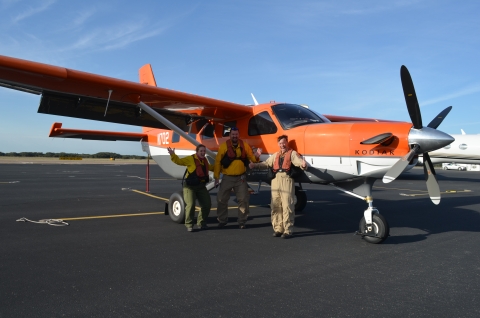 a light plane with three survey crew members on a tarmac