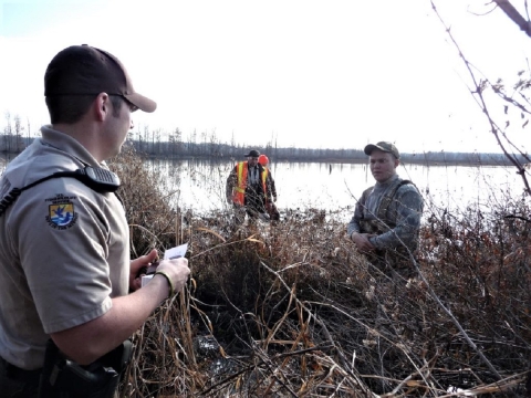 Law enforcement officer talking with hunters on lake