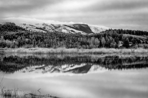 A black and white photograph of snow-covered hills above a wetland