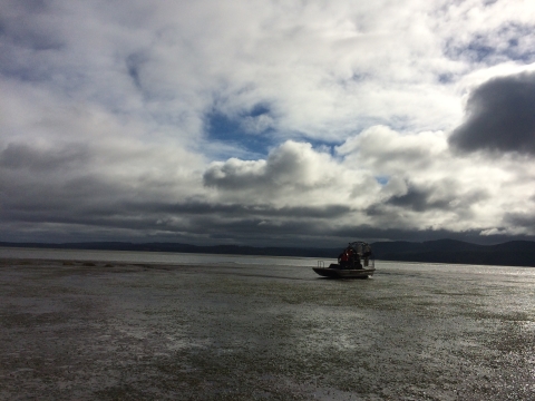 An airboat makes its way across water under a dark and cloudy sky.