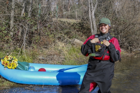 a woman posing for a photo next to a kayak