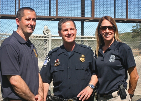 Three uniformed people smile at the camera
